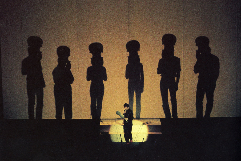 laurie anderson on stage w/violin and shadows of violin players